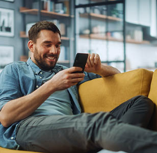 Male sitting on a couch on his phone.