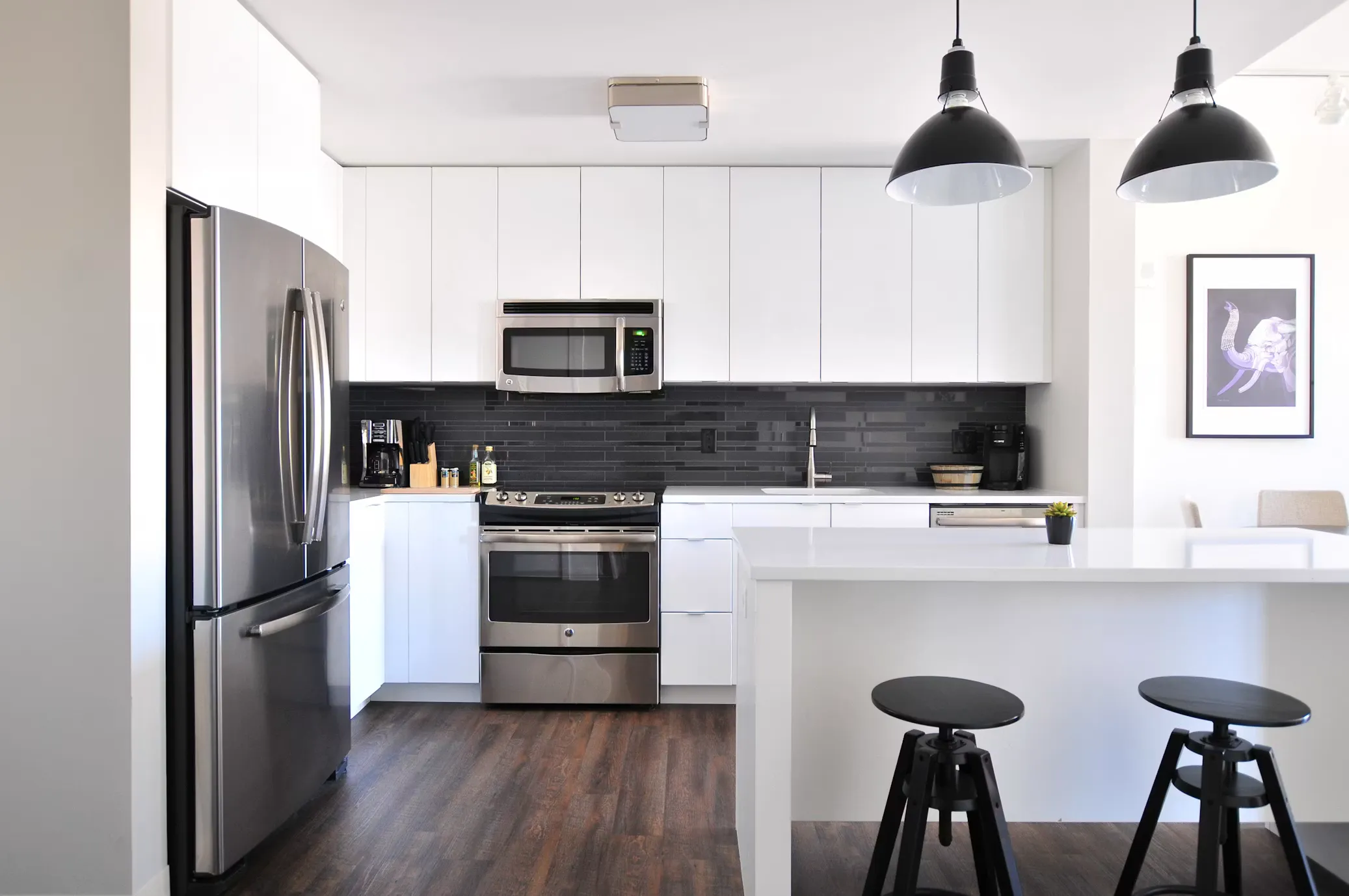 A modern kitchen featuring stainless steel appliances, white cabinetry, and a spacious island, highlighting an updated home interior