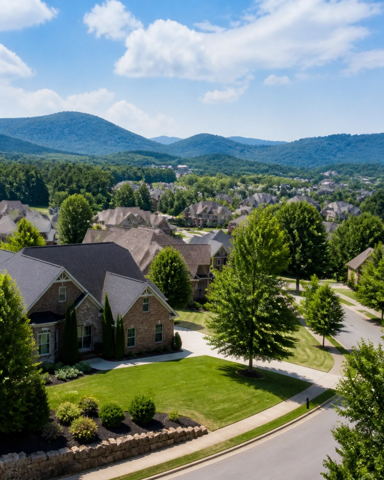 Aerial view of a beautiful suburban neighborhood with single-family homes, tree-lined streets, and scenic mountain views, showcasing an attractive residential community.
